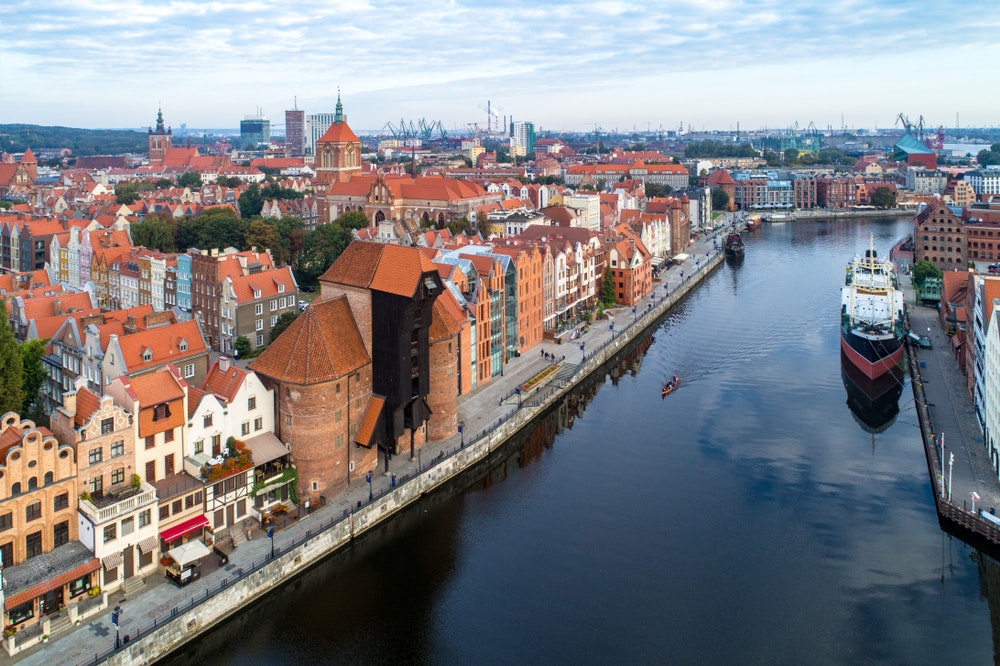 Gamlebyen i Gdansk i Polen med den eldste middelalderske havnekranen (Zuraw) i Europa, Johanneskirken, Motlawa-elven, gamle kornmagasiner, skip og en båt